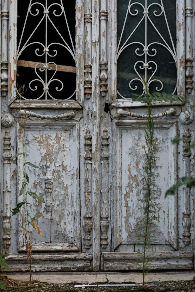 Close-up d'une porte en bois vieilli avec des ferrures décoratives, mettant en valeur son charme usé et ses détails rustiques.