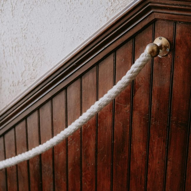 Close-up d'un escalier en panneau de bois rustique avec une rampe en corde tressée.