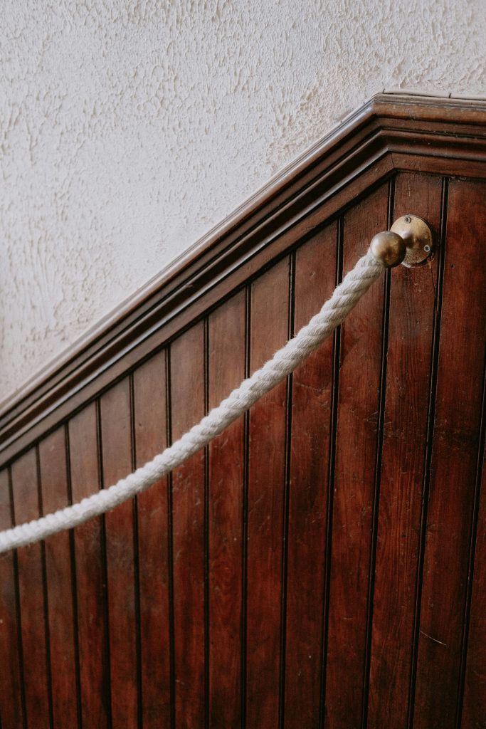 Close-up d'un escalier en panneau de bois rustique avec une rampe en corde tressée.