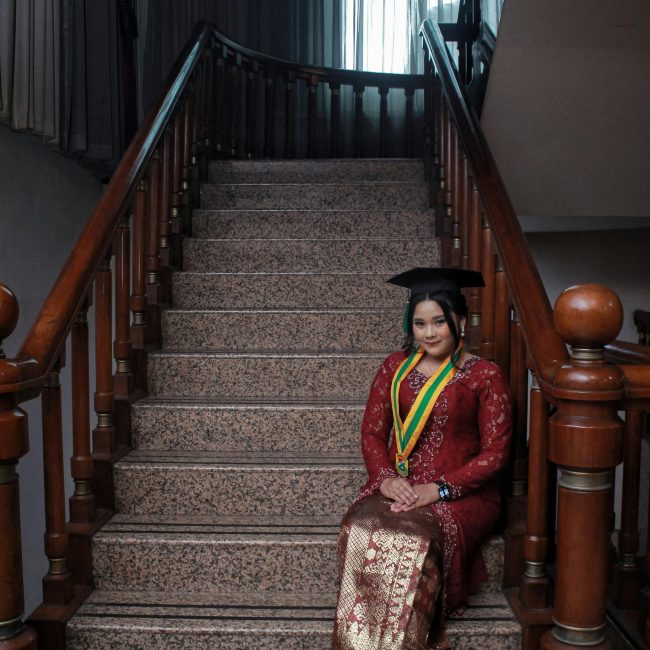 Diplômé portant une tenue traditionnelle et une toque sur un grand escalier à Jakarta