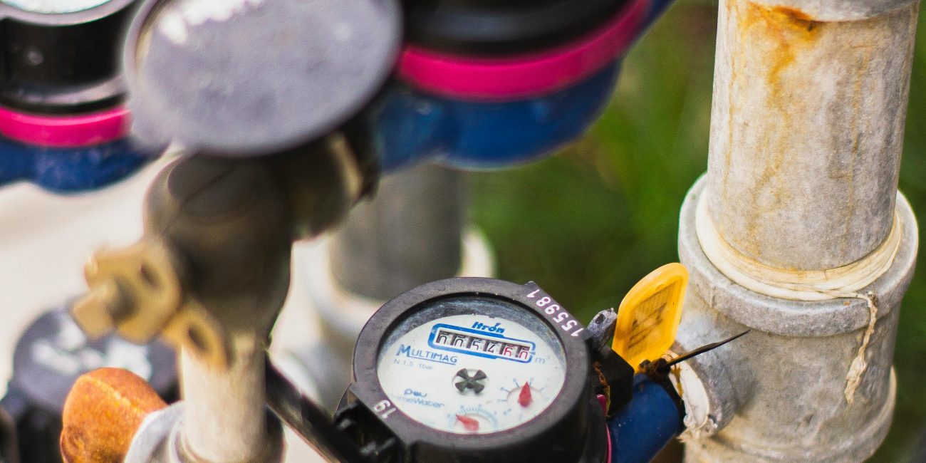 Une vue détaillée de plusieurs compteurs d'eau reliés par des tuyaux dans un cadre industriel.
