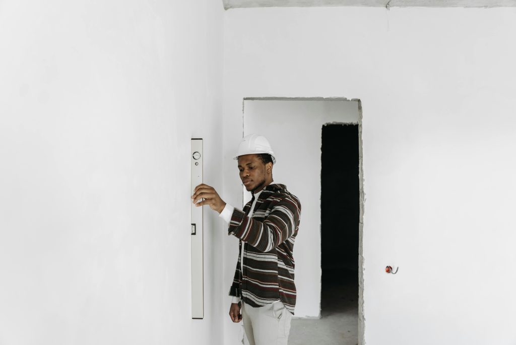 Architecte portant un casque de chantier vérifiant l'alignement d'un mur dans un projet de rénovation.