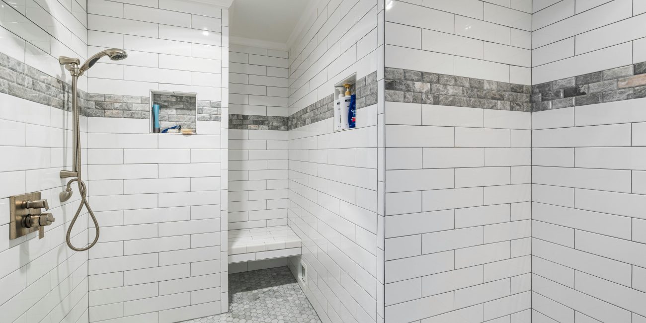 Sleek et douche à l'italienne minimaliste avec carrelage blanc et équipements modernes, sol en mosaïque.