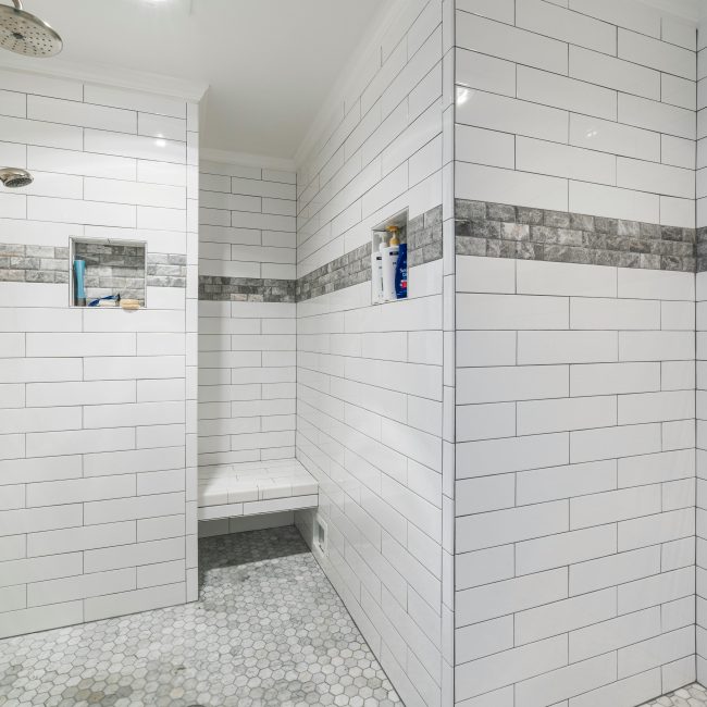 Sleek et douche à l'italienne minimaliste avec carrelage blanc et équipements modernes, sol en mosaïque.