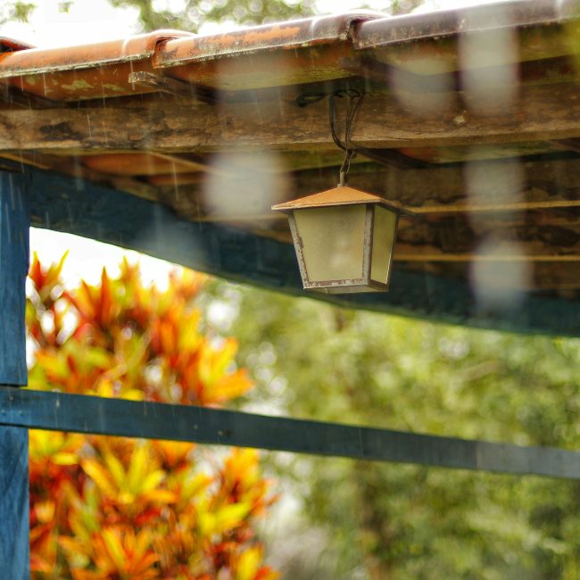 Rustique structure en bois avec une lampe suspendue sous un ciel pluvieux, offrant un cadre extérieur chaleureux