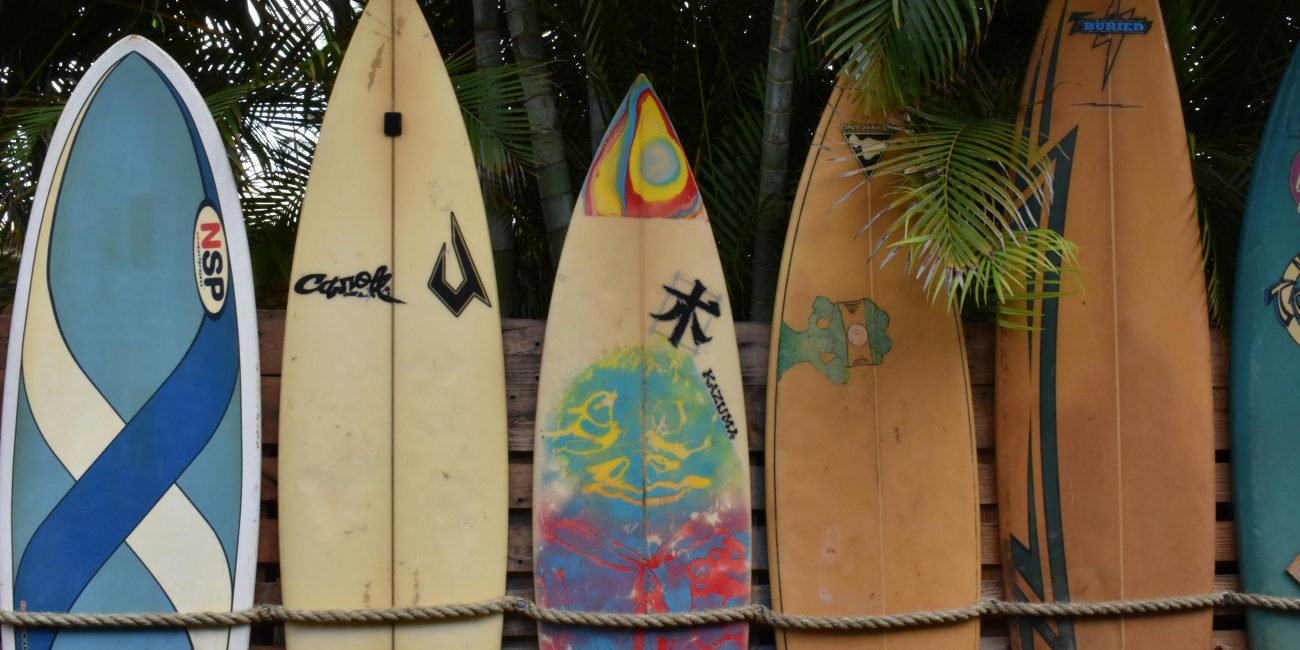 A vibrant display of surfboards leaning against a fence, perfect for summer vibes. Une exposition vibrante de planches de surf appuyées contre une clôture, parfaite pour des ambiances estivales.
