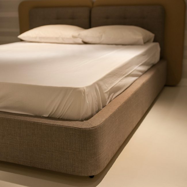 Un gros plan d'une chambre minimaliste avec un lit aux draps blancs et aux oreillers moelleux.