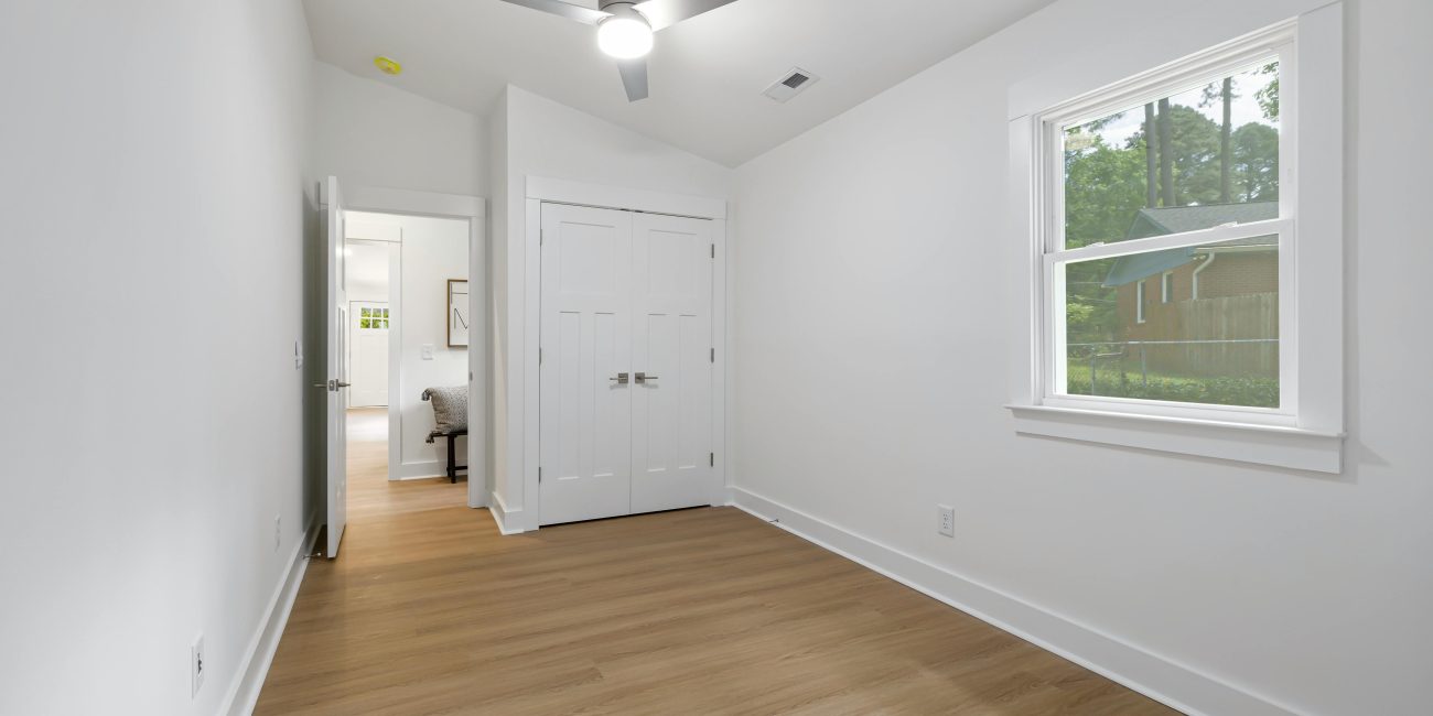 Une pièce vide minimaliste spacieuse avec un parquet en bois et une grande fenêtre laissant entrer la lumière naturelle.