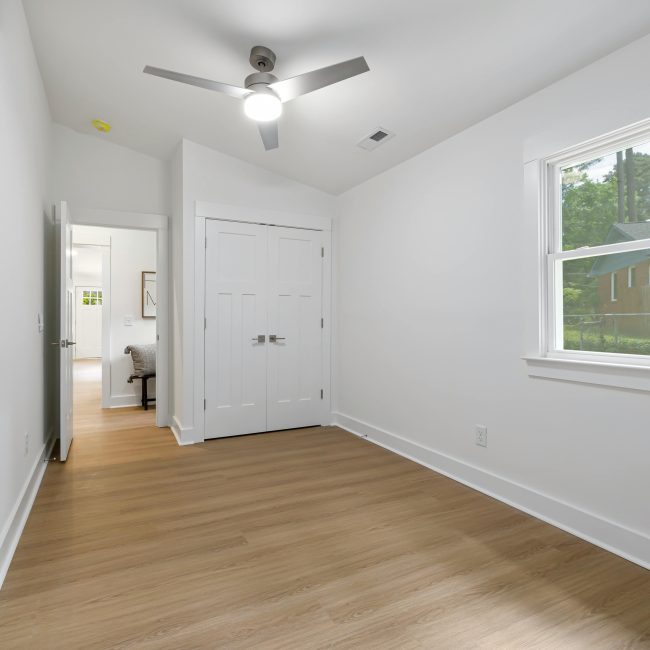 Une pièce vide minimaliste spacieuse avec un parquet en bois et une grande fenêtre laissant entrer la lumière naturelle.