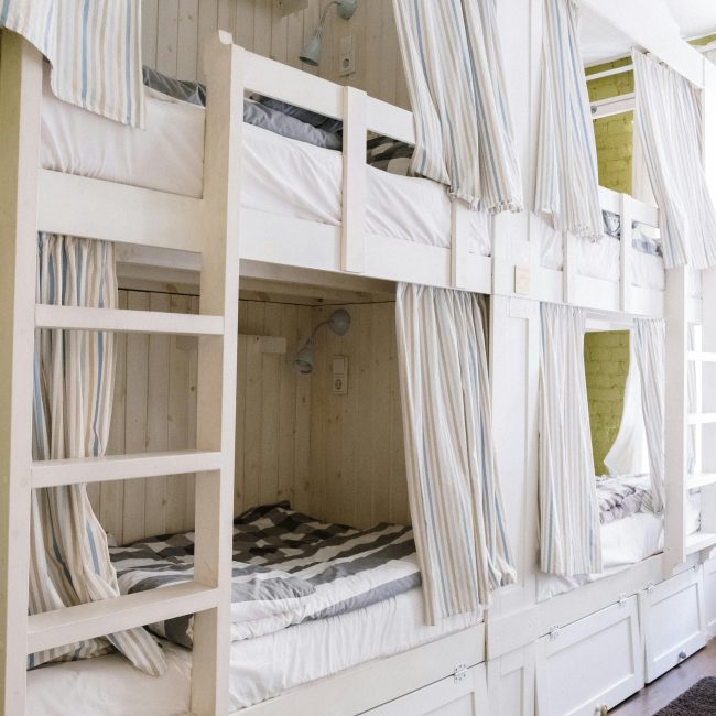 Une chambre d'étudiant moderne avec des lits superposés confortables équipés de rideaux de confidentialité et de rangements intégrés.