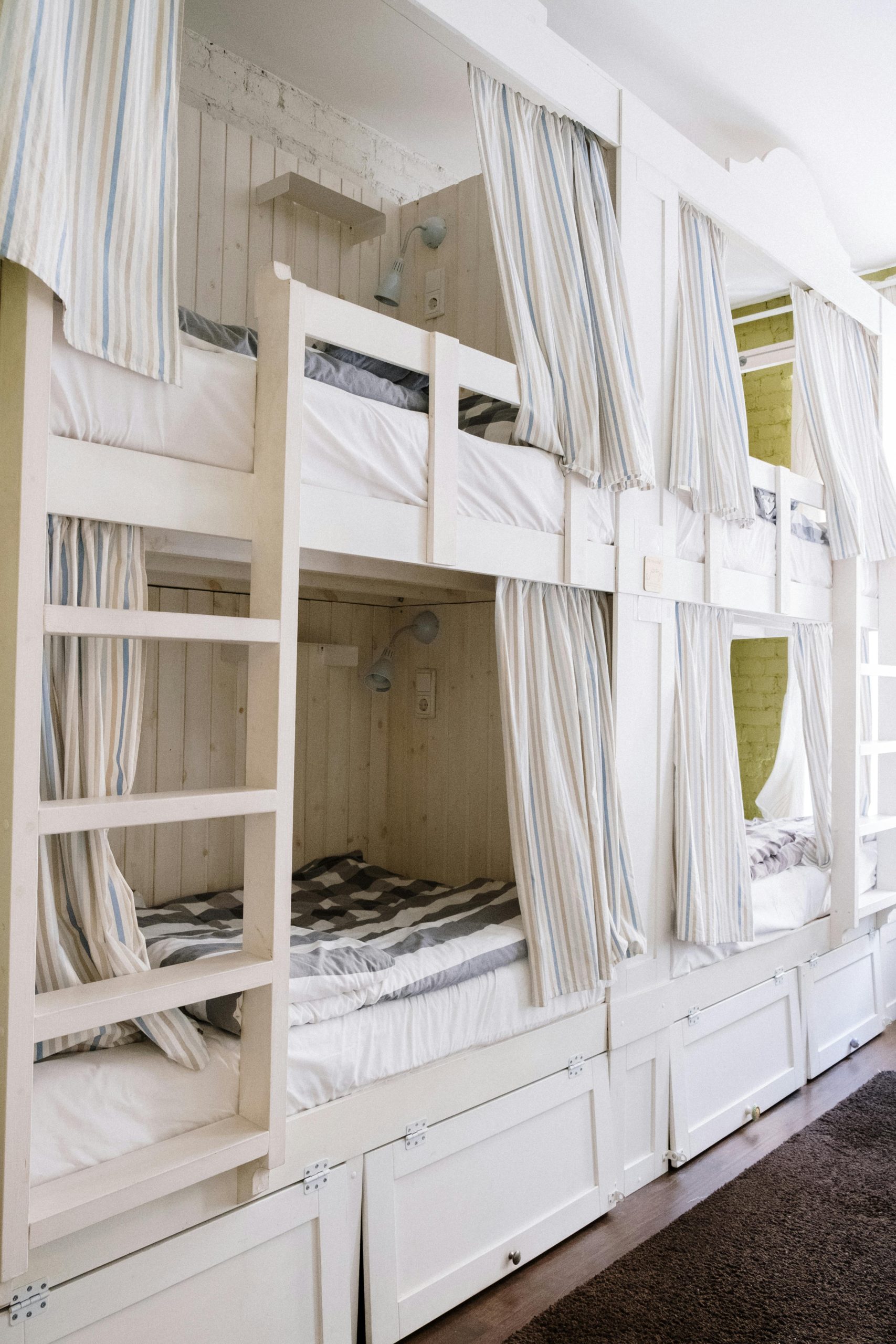 Une chambre d'étudiant moderne avec des lits superposés confortables équipés de rideaux de confidentialité et de rangements intégrés.
