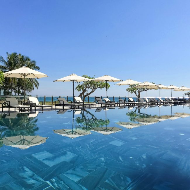 Stunning poolside view avec transats et parasols en bord de mer, parfait pour des vacances tropicales