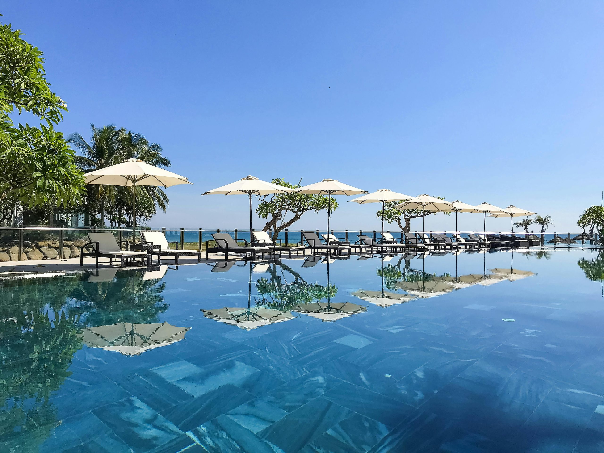 Stunning poolside view avec transats et parasols en bord de mer, parfait pour des vacances tropicales