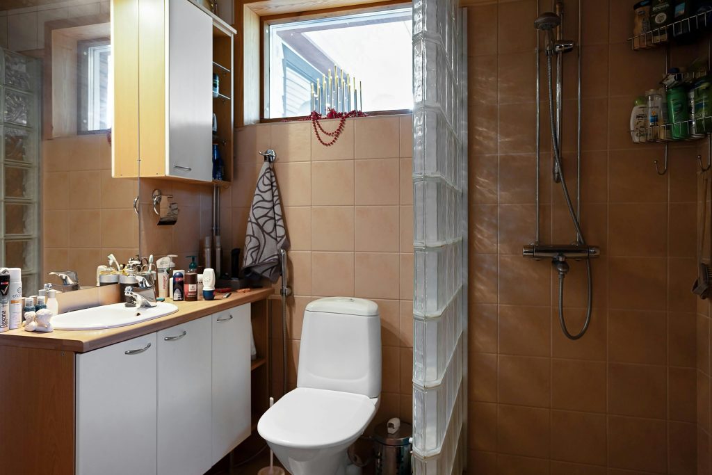 A contemporary bathroom featuring a shower, sink, and vanity with natural light from the window. Salle de bain contemporaine avec douche, lavabo et meuble de toilette baignée de lumière naturelle provenant de la fenêtre.