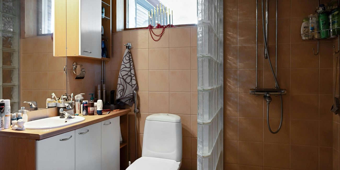 A contemporary bathroom featuring a shower, sink, and vanity with natural light from the window. Salle de bain contemporaine avec douche, lavabo et meuble de toilette baignée de lumière naturelle provenant de la fenêtre.
