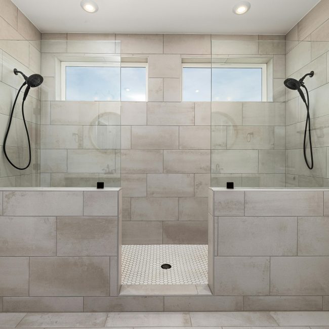 Une salle de bain contemporaine à double douche élégante, mettant en valeur des carreaux raffinés et des installations modernes.