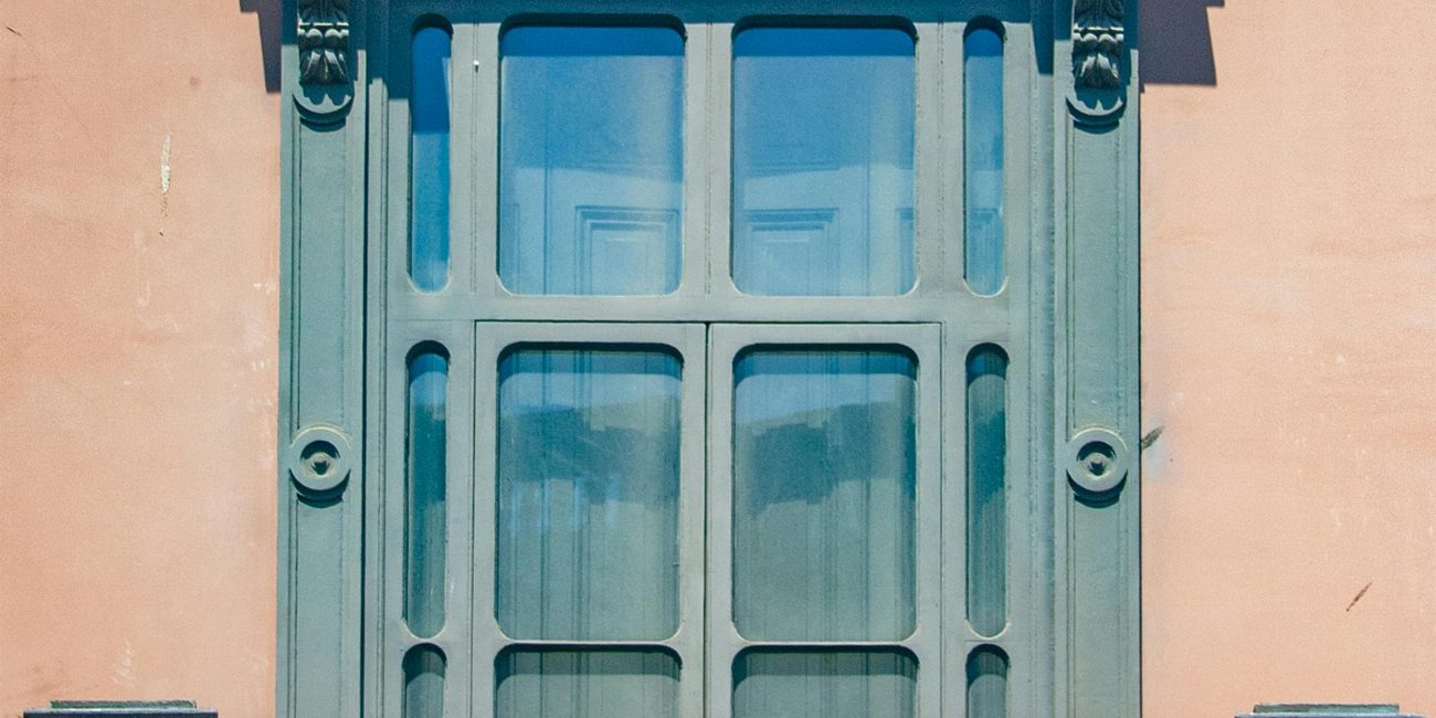 Close-up d'un balcon ensoleillé orné avec des détails architecturaux classiques sur un mur urbain.