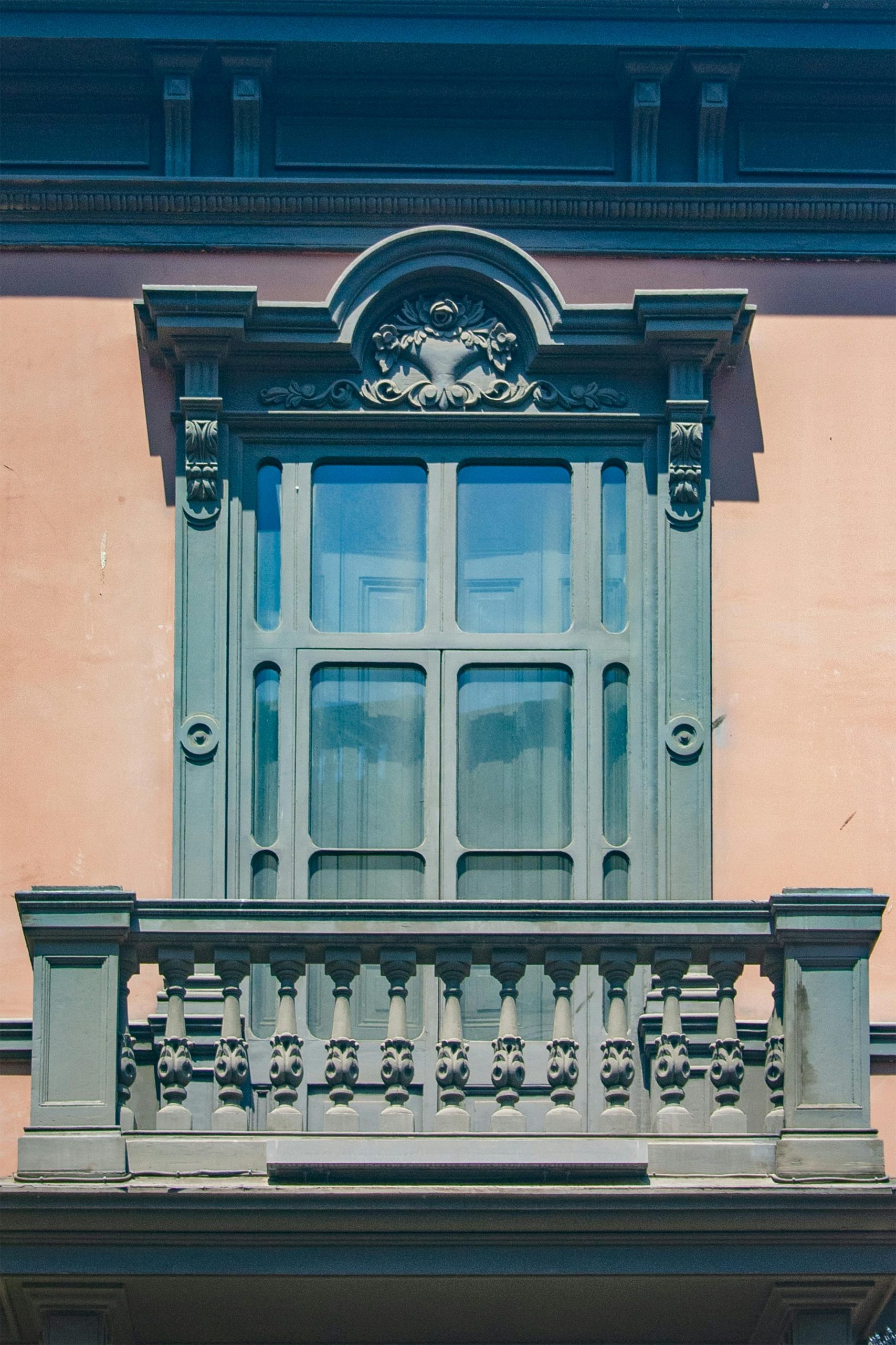 Close-up d'un balcon ensoleillé orné avec des détails architecturaux classiques sur un mur urbain.
