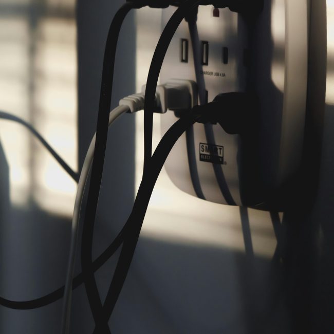 Multiple câbles de charge branchés dans une prise murale, illustrant la connectivité énergétique.