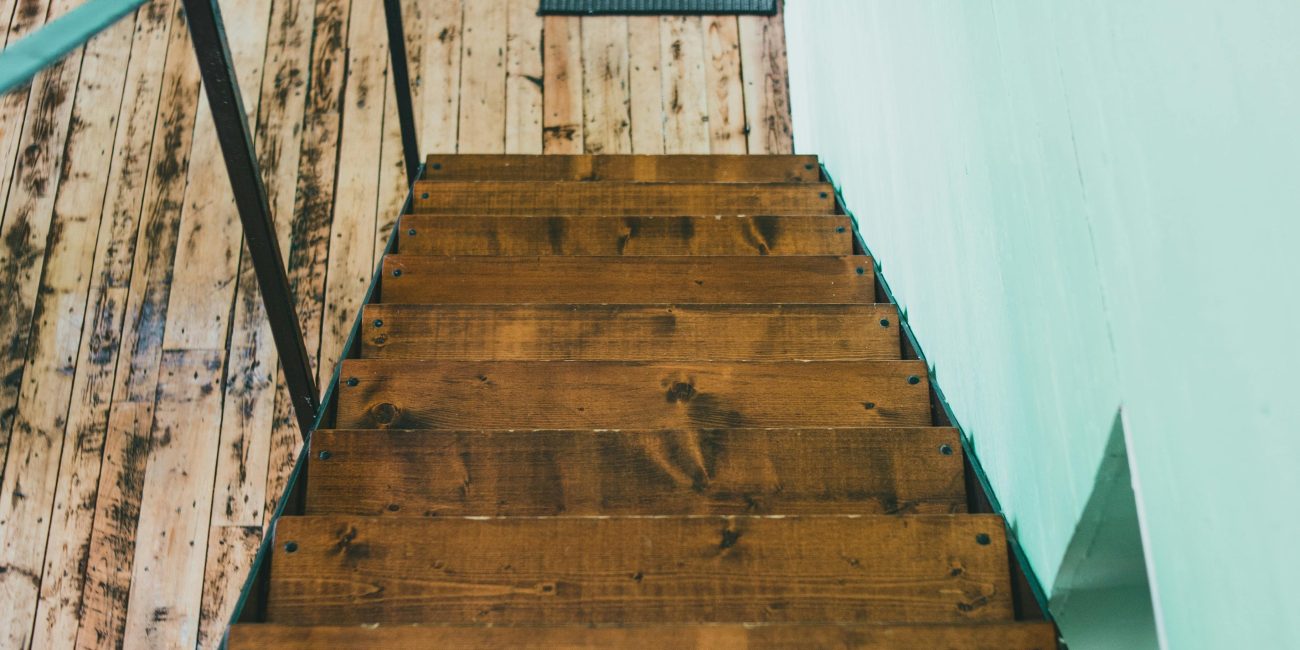 Top-down view d'un escalier en bois rustique contre des murs verts menthe à l'intérieur.