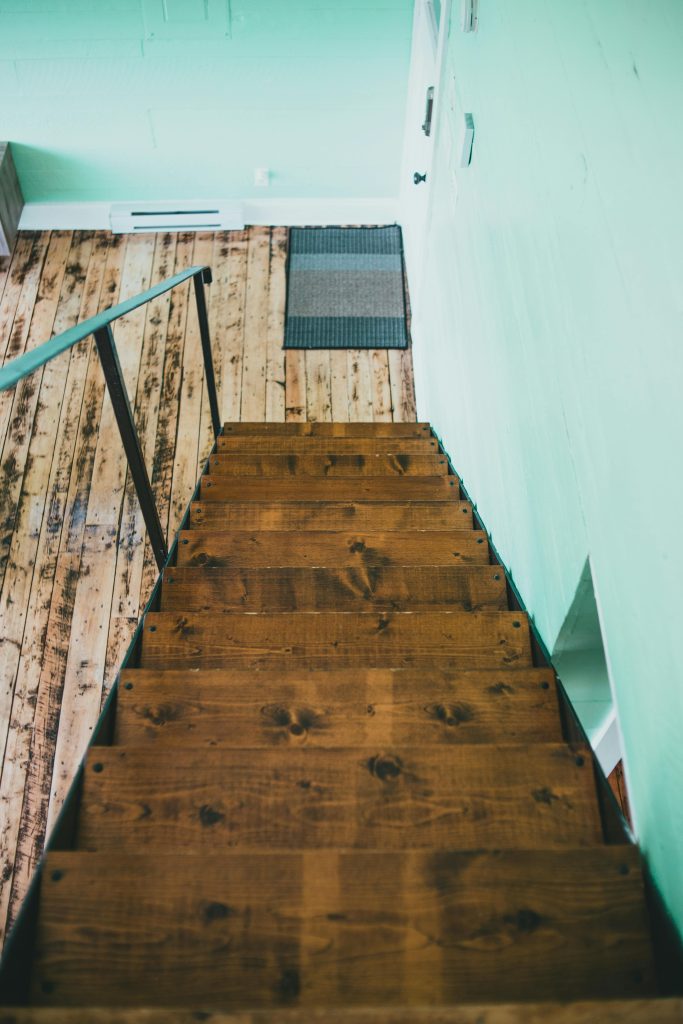 Top-down view d'un escalier en bois rustique contre des murs verts menthe à l'intérieur.