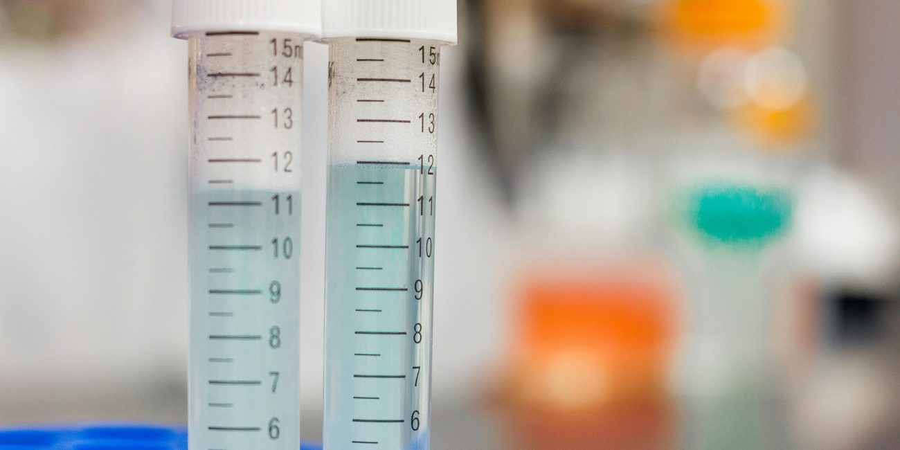 Focused image de deux éprouvettes de laboratoire contenant du liquide, parfaite pour les thèmes scientifiques et de recherche.