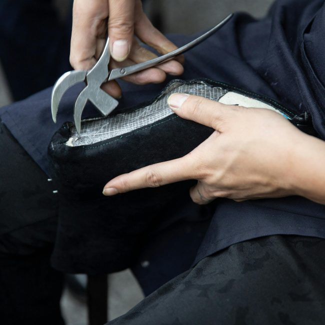 Rapprochement d'un artisan réparant une chaussure en cuir avec une pince de cordonnier.