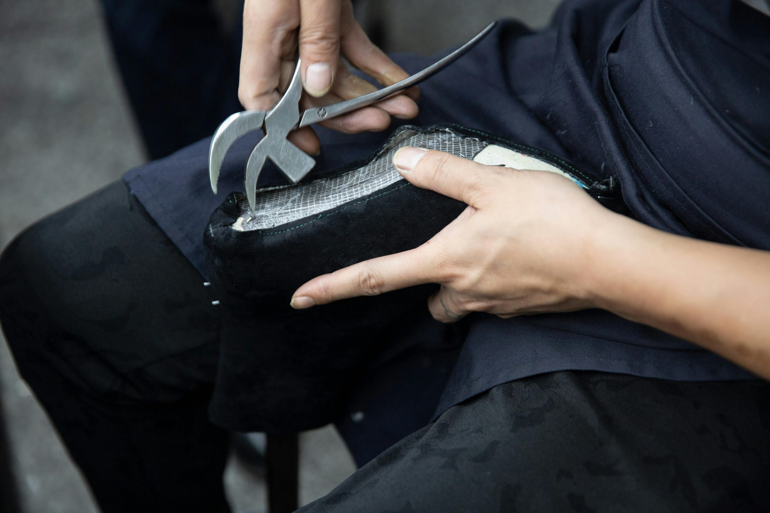 Rapprochement d'un artisan réparant une chaussure en cuir avec une pince de cordonnier.