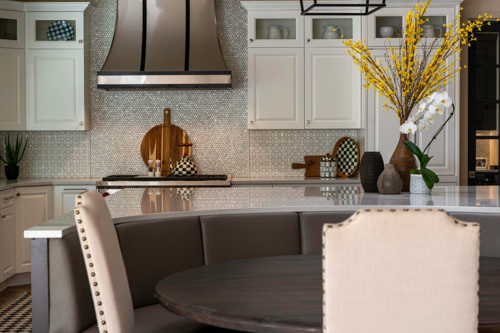 Une cuisine moderne avec des placards élégants, une table ronde et des éléments décoratifs comme des fleurs et des vases.