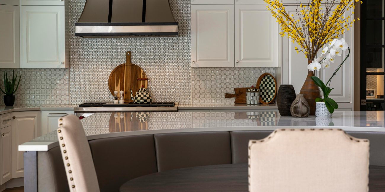 Une cuisine moderne avec des placards élégants, une table ronde et des éléments décoratifs comme des fleurs et des vases.