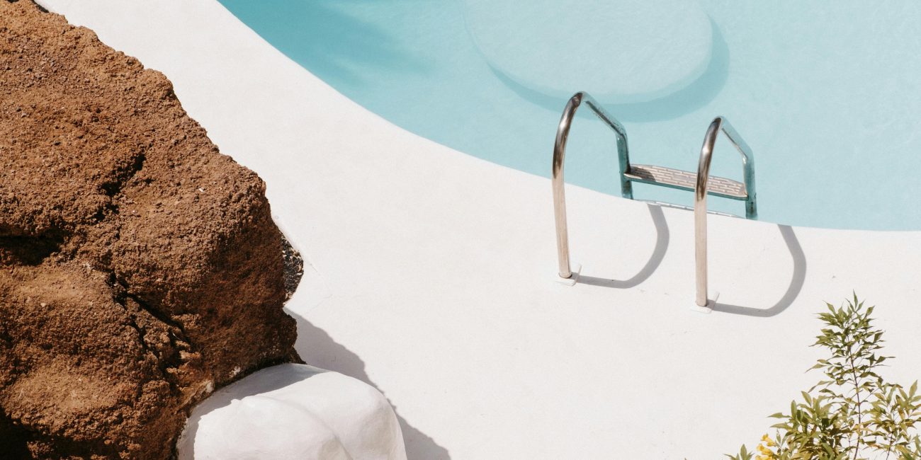 A tranquil scene with a clear blue pool surrounded by natural rocks and minimal vegetation. Scène tranquille avec une piscine bleue claire entourée de rochers naturels et d'une végétation minimale.