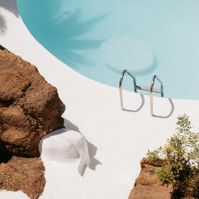 A tranquil scene with a clear blue pool surrounded by natural rocks and minimal vegetation. Scène tranquille avec une piscine bleue claire entourée de rochers naturels et d'une végétation minimale.