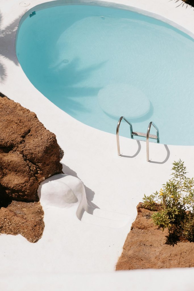 A tranquil scene with a clear blue pool surrounded by natural rocks and minimal vegetation. Scène tranquille avec une piscine bleue claire entourée de rochers naturels et d'une végétation minimale.