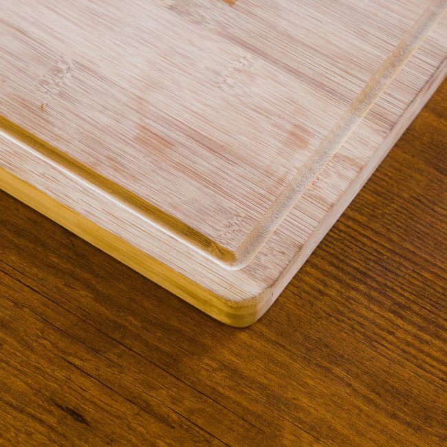 Plan rapproché d'une planche à découper en bambou naturel sur une surface en bois texturée.