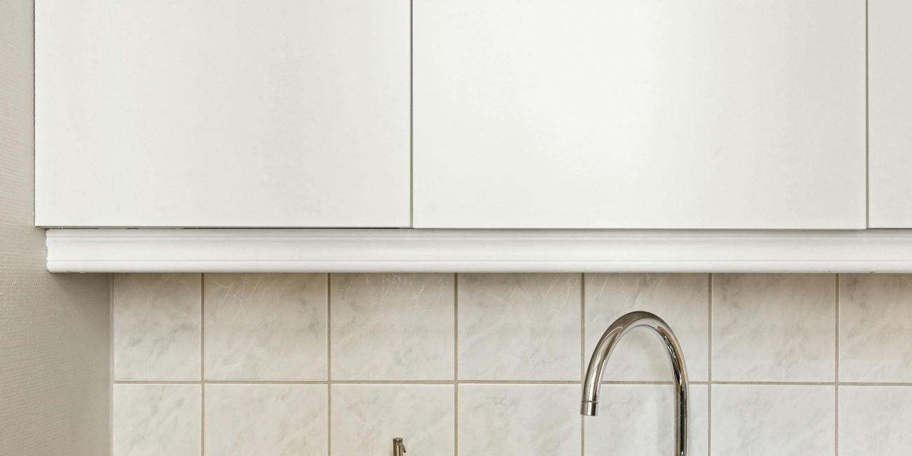 Cuisine minimaliste élégante avec évier en acier inoxydable, citron et armoires blanches.