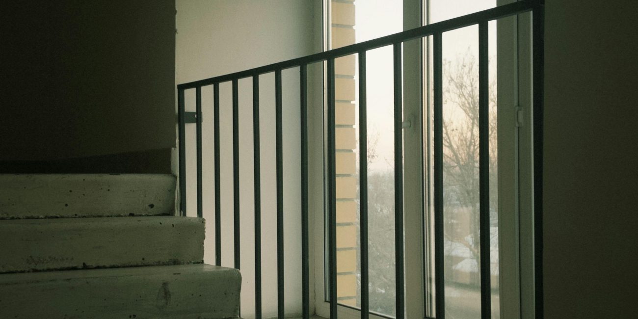 Escaliers en béton avec vue par une fenêtre créant une ambiance minimaliste.