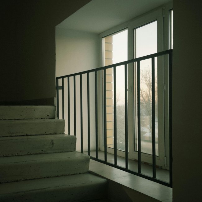 Escaliers en béton avec vue par une fenêtre créant une ambiance minimaliste.