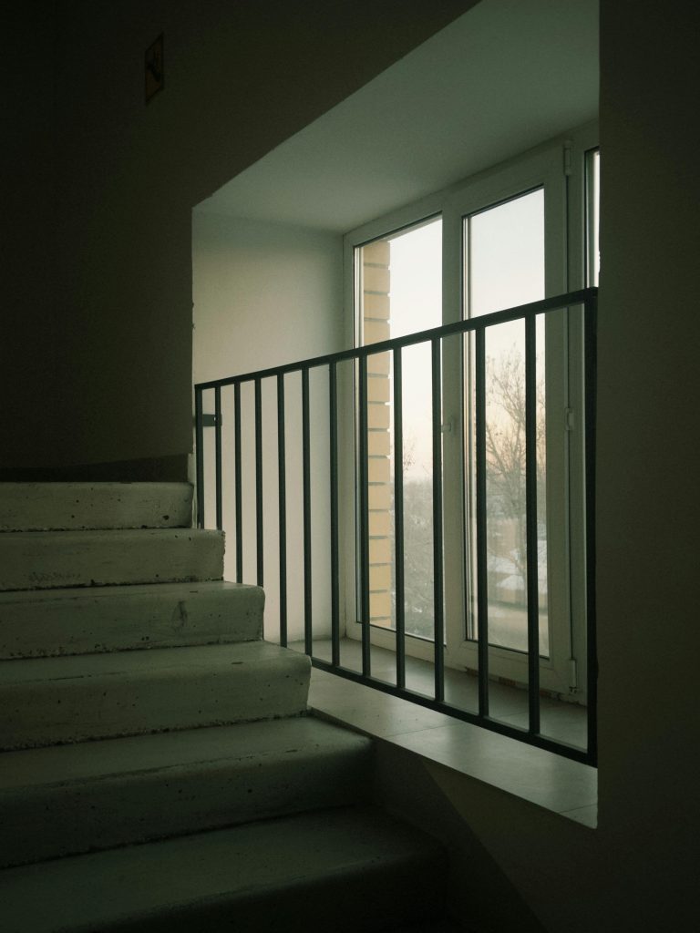 Escaliers en béton avec vue par une fenêtre créant une ambiance minimaliste.