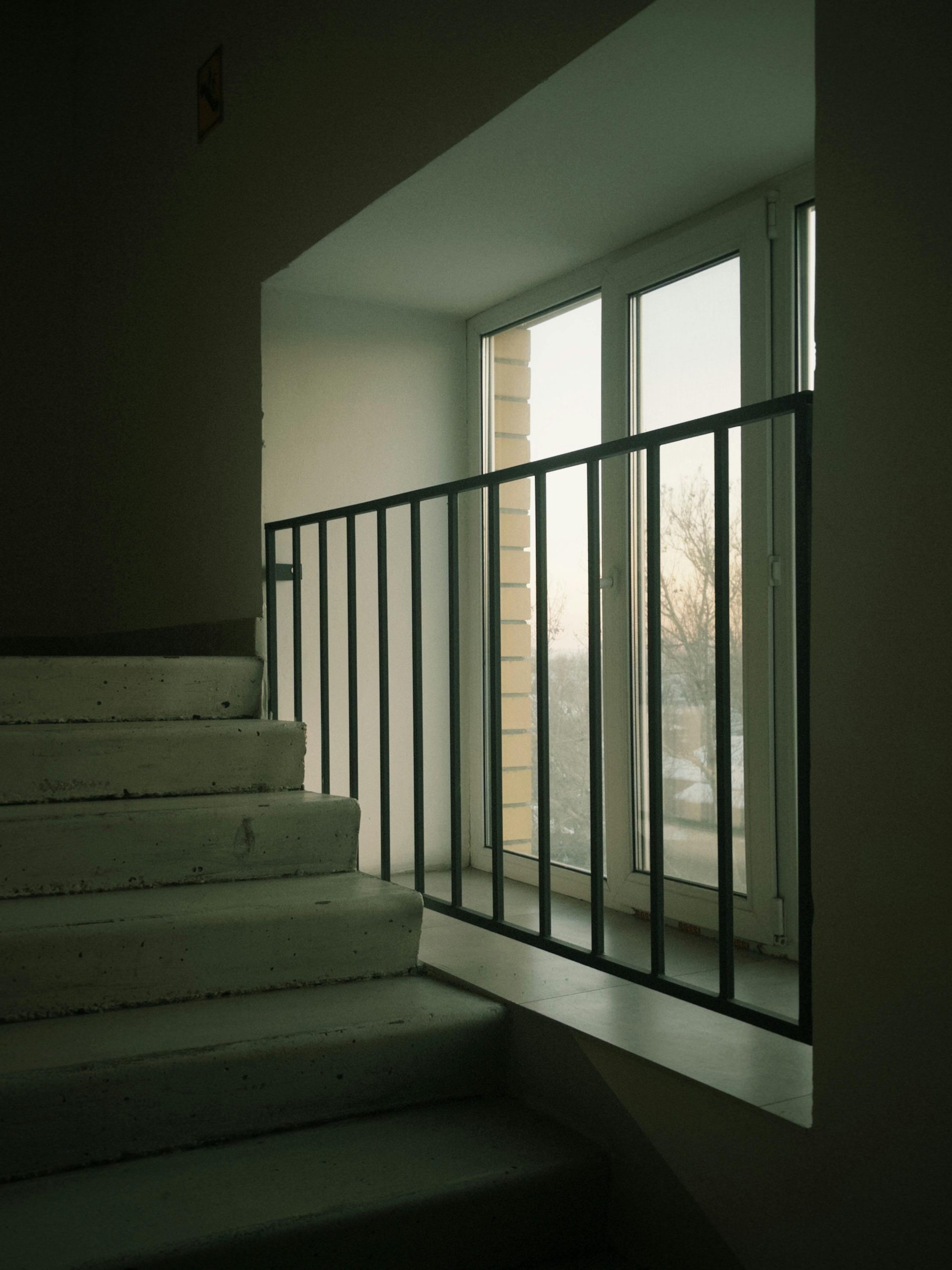 Escaliers en béton avec vue par une fenêtre créant une ambiance minimaliste.