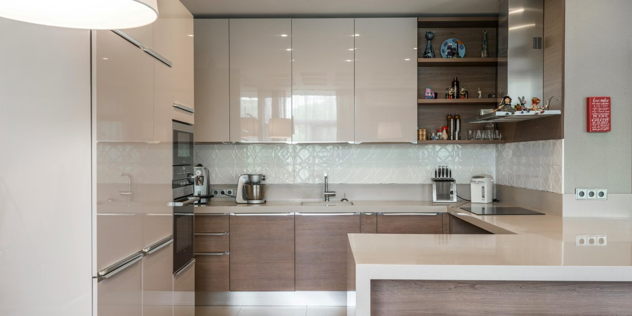 Sleek modern kitchen avec des placards blancs, un îlot et des appareils encastrés.