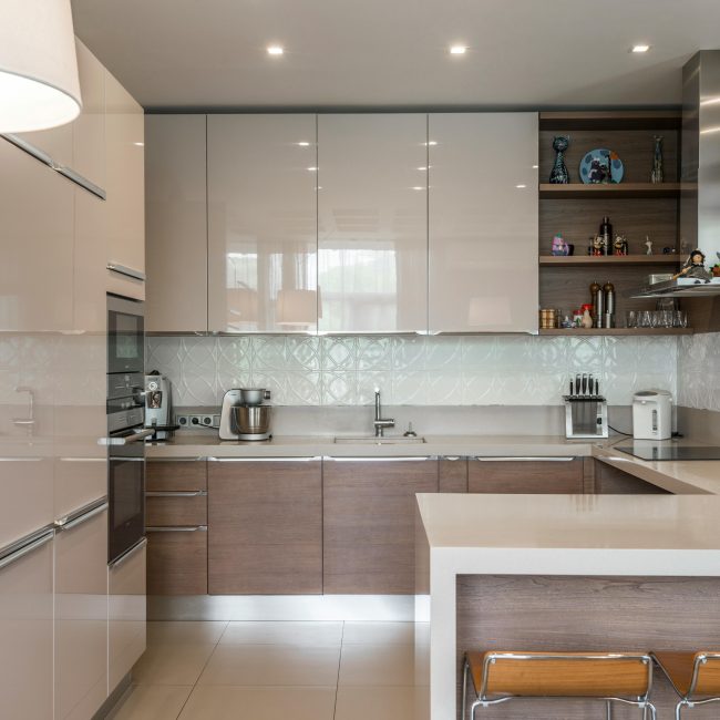 Sleek modern kitchen avec des placards blancs, un îlot et des appareils encastrés.