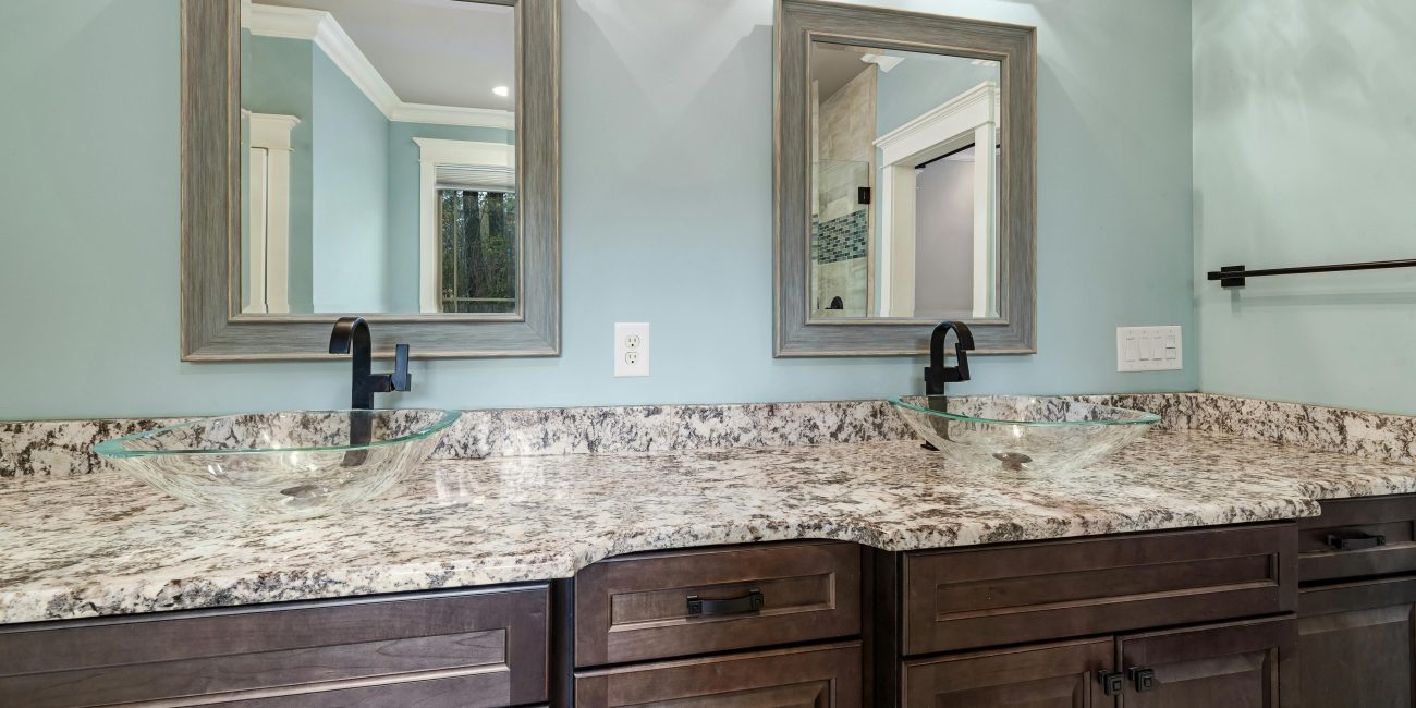 Stylish bathroom featuring dual glass bowl sinks and granite countertops. Salle de bain élégante avec deux vasques en verre et des plans de travail en granit.