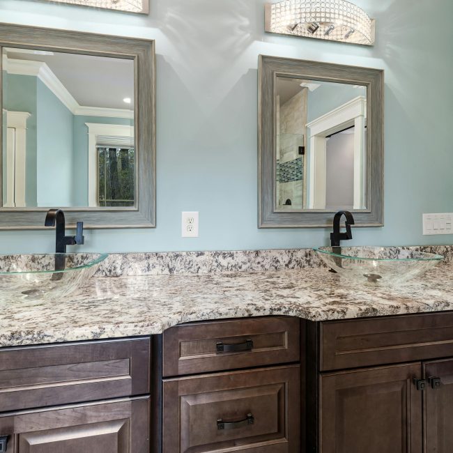 Stylish bathroom featuring dual glass bowl sinks and granite countertops. Salle de bain élégante avec deux vasques en verre et des plans de travail en granit.