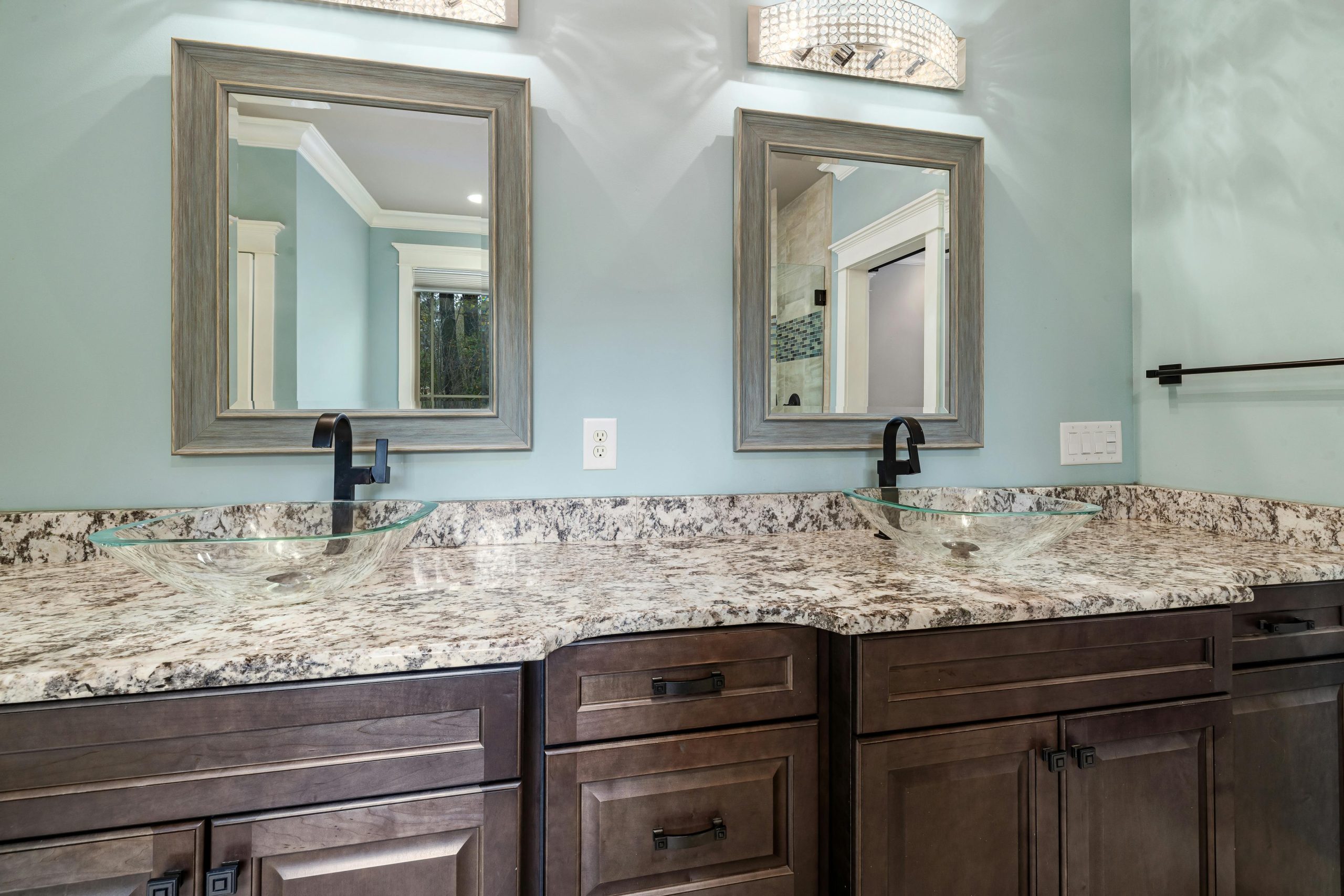 Stylish bathroom featuring dual glass bowl sinks and granite countertops. Salle de bain élégante avec deux vasques en verre et des plans de travail en granit.
