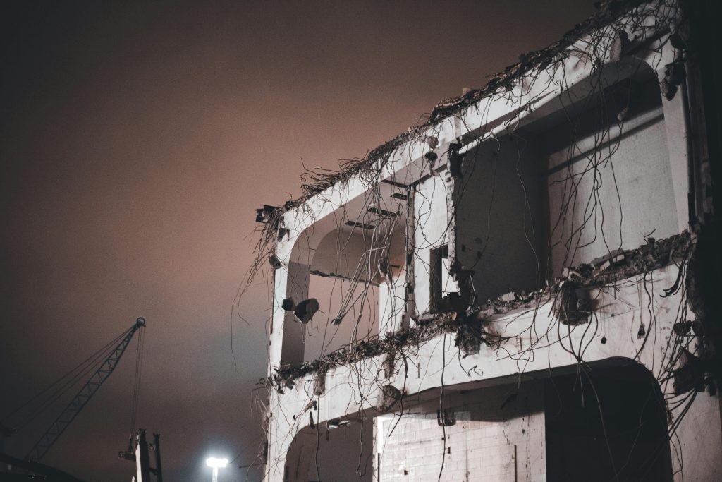 Une image inquiétante d'un bâtiment partiellement démoli de nuit avec des fils électriques exposés.