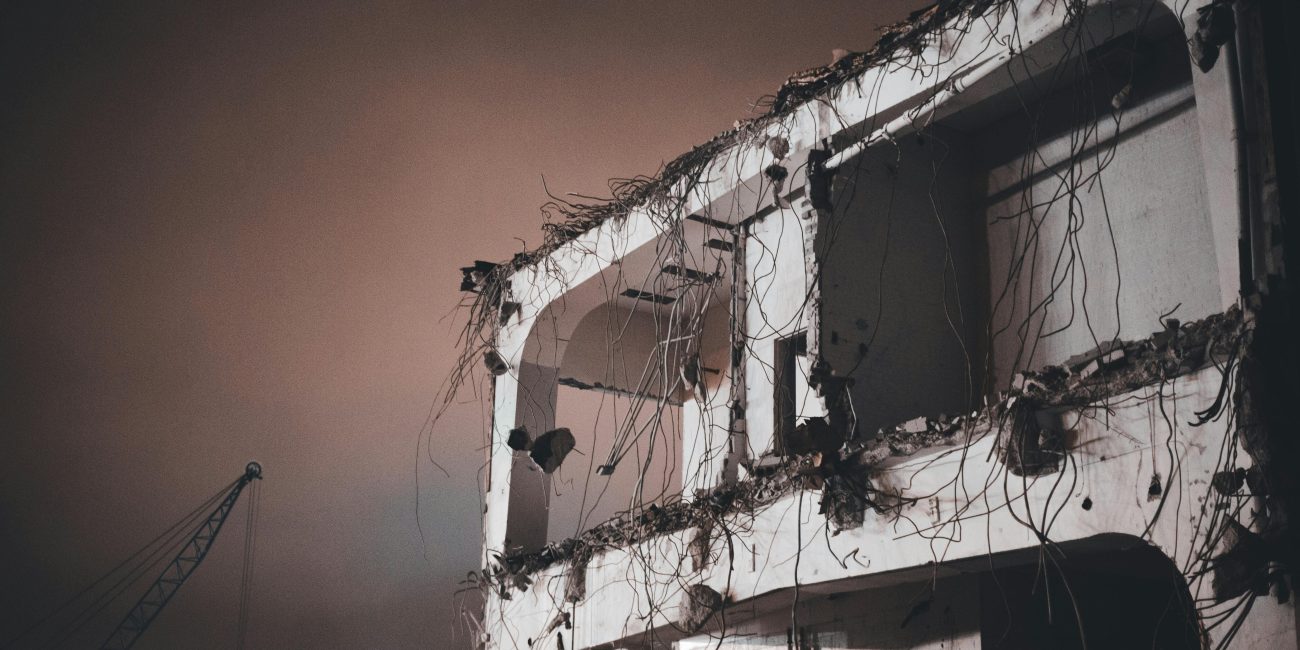 Une image inquiétante d'un bâtiment partiellement démoli de nuit avec des fils électriques exposés.