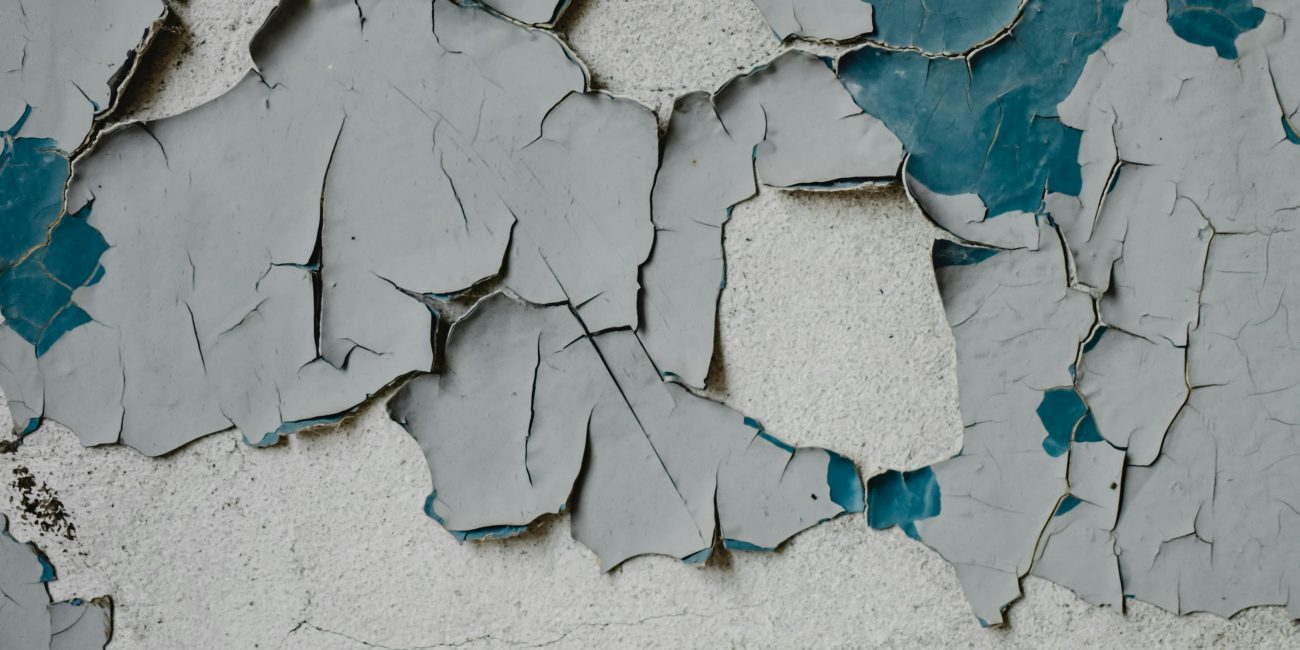 Close-up de peinture écaillée texturée sur un vieux mur en béton, révélant des couches.