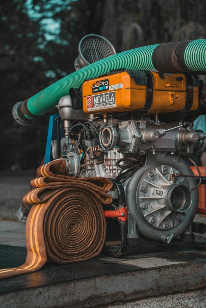 Détail d'une pompe industrielle avec un tuyau enroulé, idéale pour les projets d'eau et d'utilité publique.