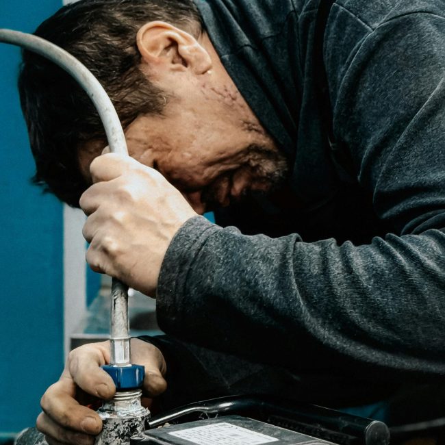 A technician concentrates on adjusting a water pump indoors. Un technicien se concentre sur l'ajustement d'une pompe à eau à l'intérieur.
