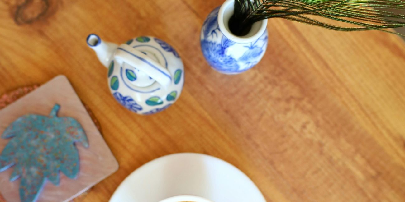 Top view of coffee cup, peacock feather, and ceramics on a table. Vue de dessus d'une tasse de café, d'une plume de paon et de céramiques sur une table.